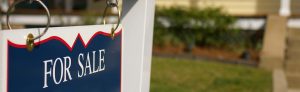 A white and blue "for sale" sign for a home